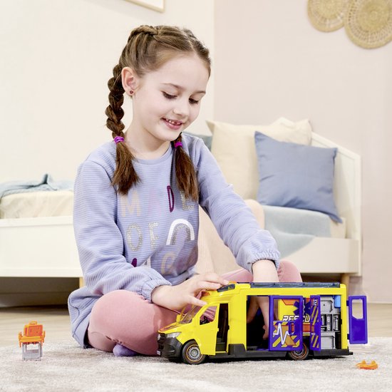 Meisje met vlechten speelt met gele ambulance met open deuren en medische accessoires.