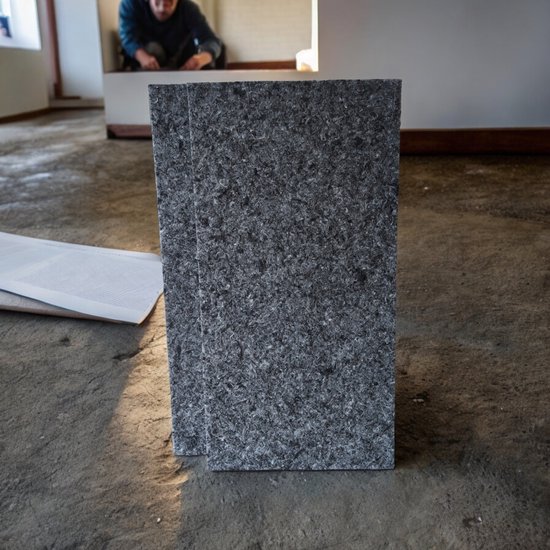 Twee verticale, donkergrijze, vezelige akoestische panelen op een betonnen vloer.