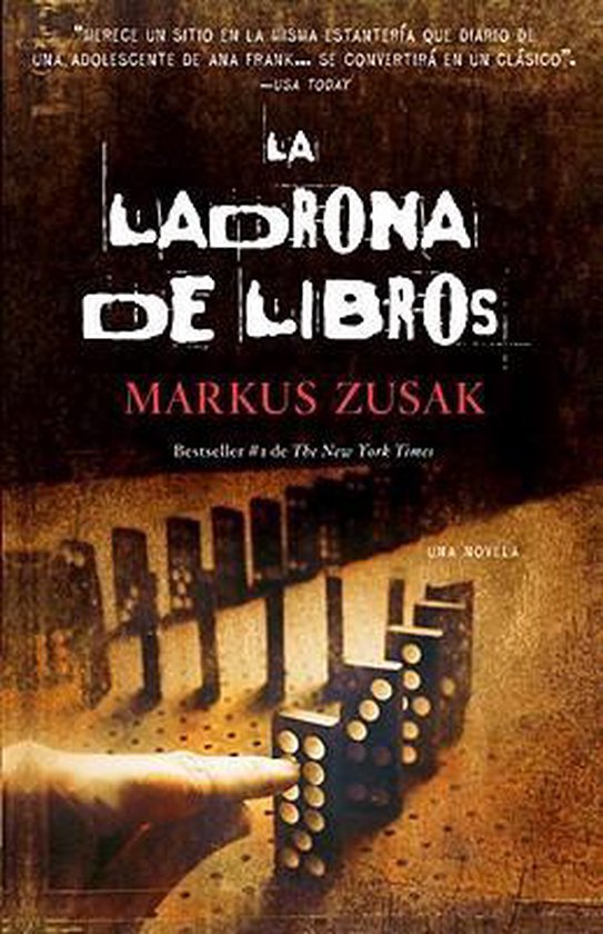 Boekomslag met de titel 'LA LADRONA DE LIBROS' en 'MARKUS ZUSAK' in distressed letters. Een hand duwt dominostenen om.