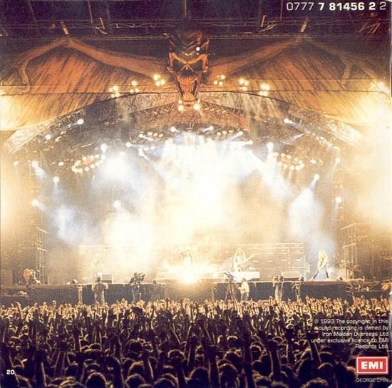 Een rockconcert met een groot podium, veel lichten, een drakenhoofd decor en een uitbundige menigte.