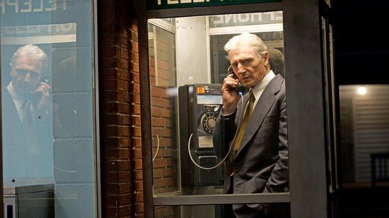 Een man in een pak belt in een telefooncel.