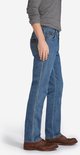 Zijaanzicht van een blauwe regular fit jeans met bruine schoenen.