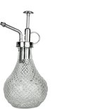 Een heldere glazen plantenspuit met zilverkleurig metalen sproeimechanisme en decoratief reliëf.