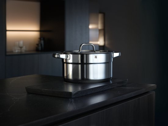 Een RVS pan met deksel staat op een marmeren aanrecht in een moderne keuken.
