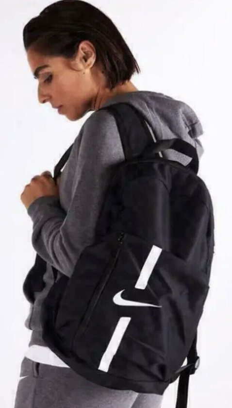 Vrouw draagt zwarte Nike rugzak met witte strepen.
