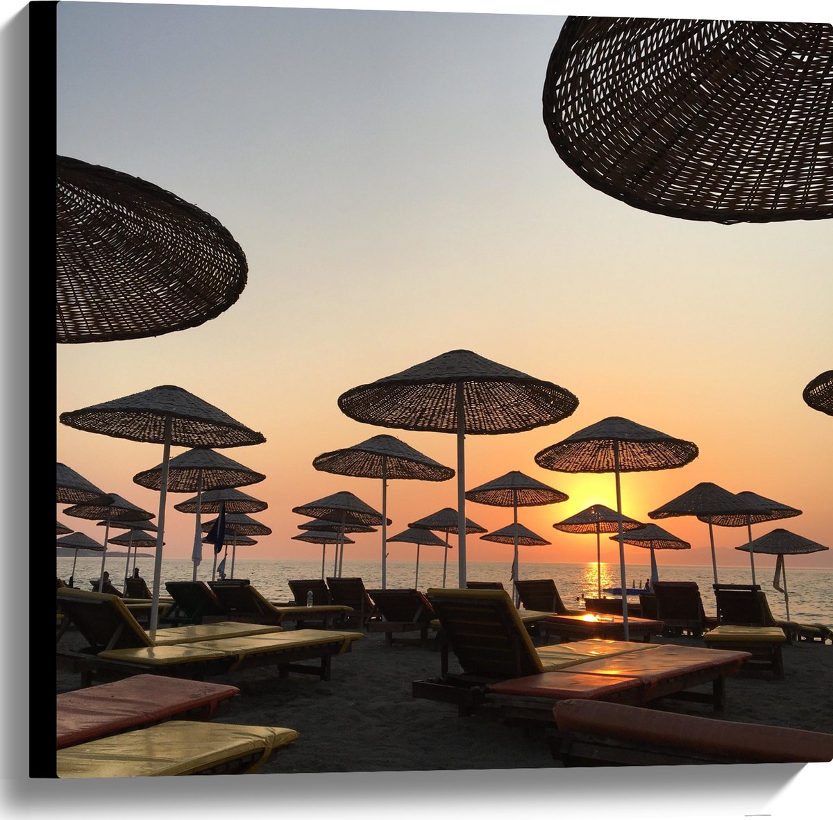 Canvas - Ligbedden met Rieten Parasols aan het Strand in de Avondzon - 60x60 cm Foto op Canvas Schilderij (Wanddecoratie op Canvas)
