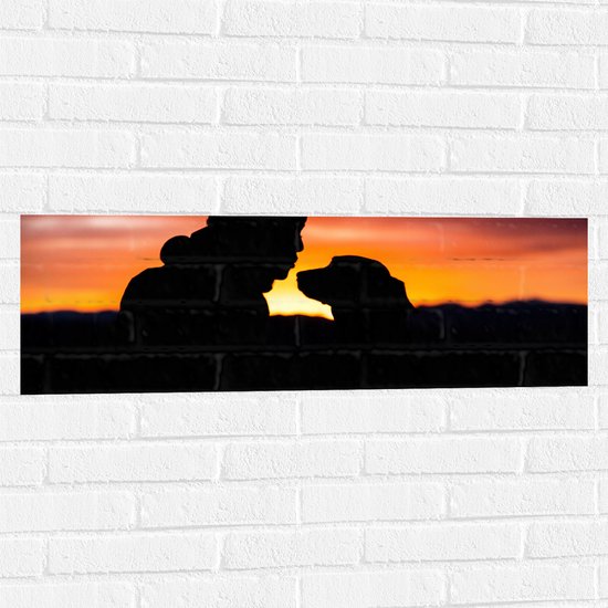 WallClassics - Muursticker - Silhouet van Man met Muts met Zijn Hond - 90x30 cm Foto op Muursticker