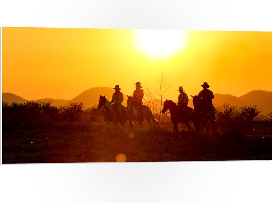 PVC Schuimplaat- Groepje Cowboys op Paarden Rijdend door Landschap bij de Ondergaande Zon - 100x50 cm Foto op PVC Schuimplaat