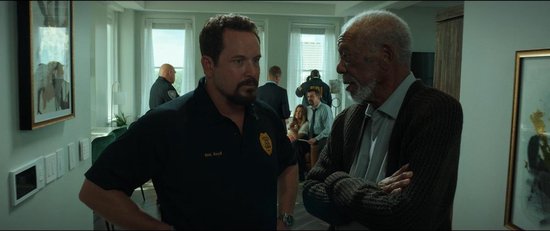 Twee mannen in gesprek; links een man in een zwart shirt, rechts Morgan Freeman.