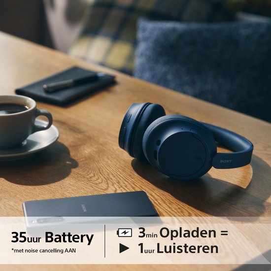 Blauwe Sony WH-CH720N koptelefoon op tafel, met smartphone en koffie.