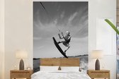 Behang - Fotobehang Een vrouw maakt een sprong in de lucht met haar wakeboard - zwart wit - Breedte 155 cm x hoogte 240 cm