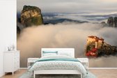Behang - Fotobehang De Meteora kloosters in een wolkengordijn - Breedte 330 cm x hoogte 220 cm