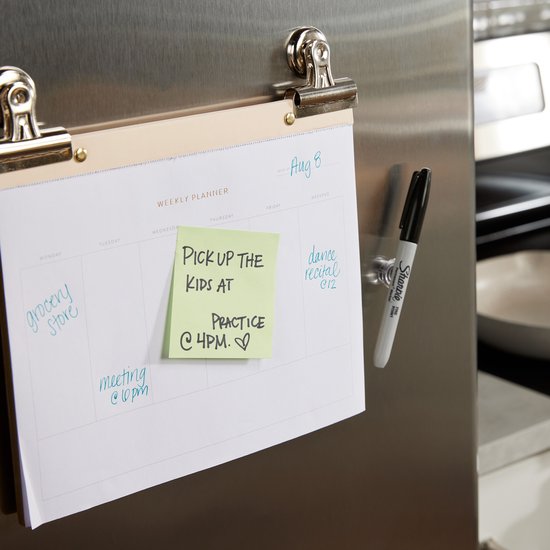 Een wekelijkse planner gehangen aan een koelkastdeur met een zwarte Sharpie marker ernaast.