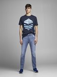 Man in donkerblauw t-shirt met Jack & Jones print en lichtblauwe jeans. Staand, vooraanzicht.