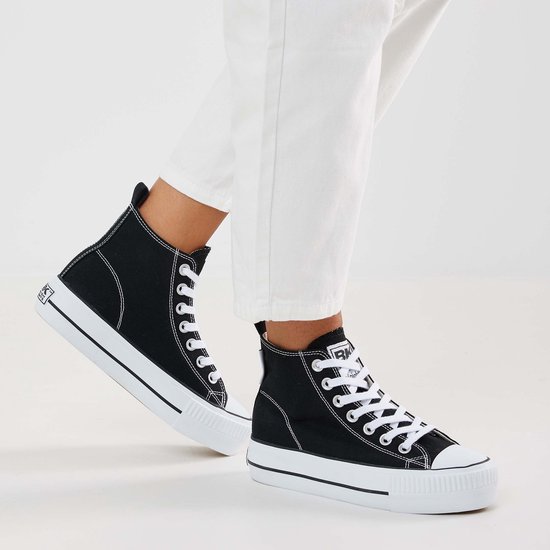 Vrouwen met witte jeans dragen zwarte hoge sneakers met witte veters en dikke witte zolen.