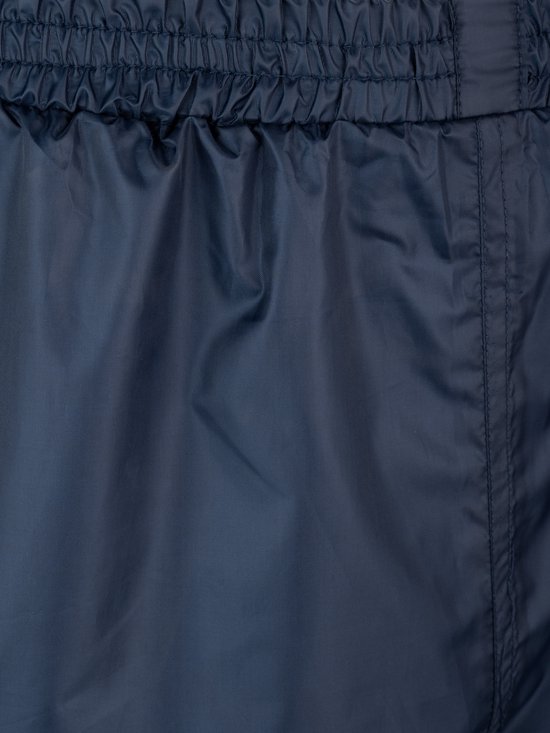 Detail van de elastische tailleband van de donkerblauwe regenbroek.