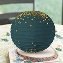 Donkergroene lampion met gouden stippen op een boek.