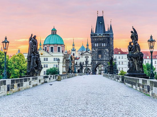 De Karelsbrug in Praag bij zonsopgang, met standbeelden en de Oude Stadsbrugtoren.
