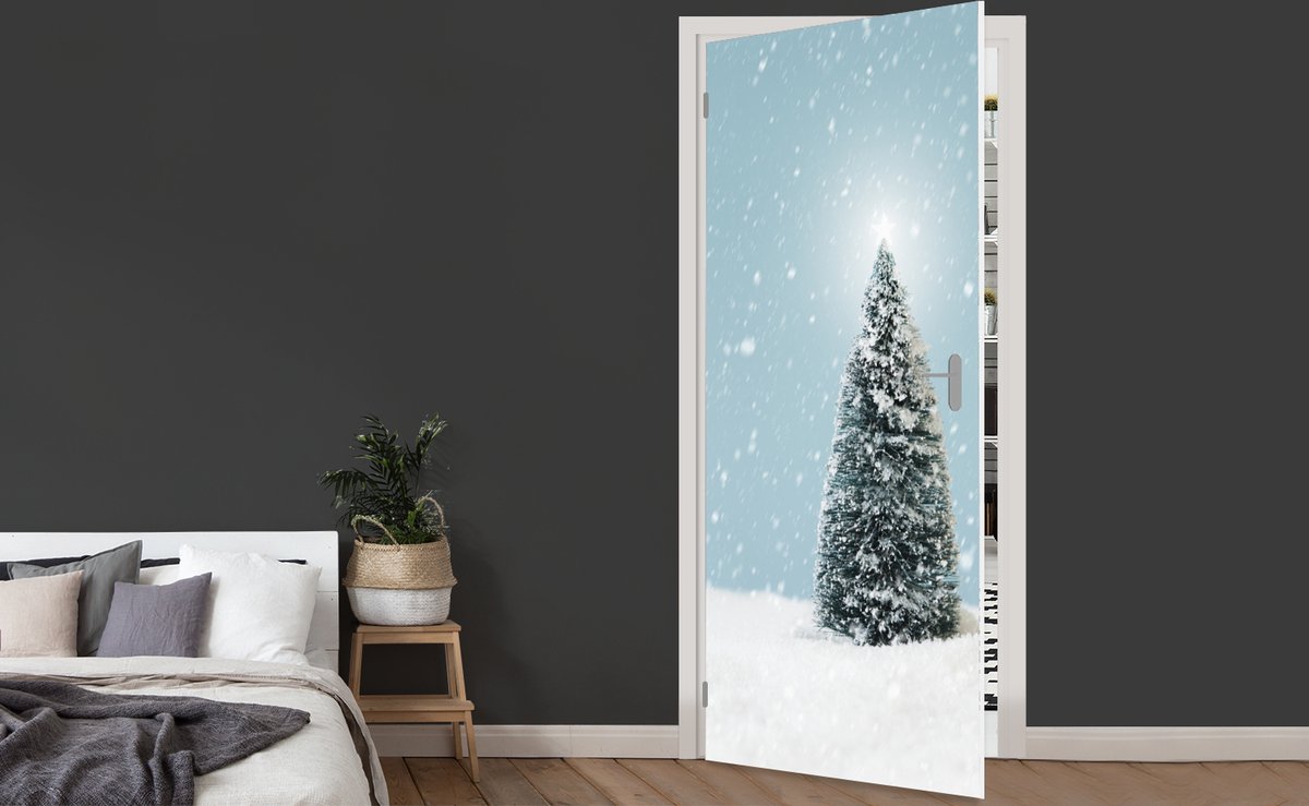 Afbeelding van product StickerSnake  Deursticker Een kerstboom in een besneeuwd landschap en een blauwe hemel - 90x205 cm - Deurposter