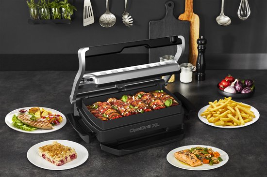 Open OptiGrill XL met bakplaat vol kiprolletjes, met gegrilde kip, zalm, taart en friet ernaast.