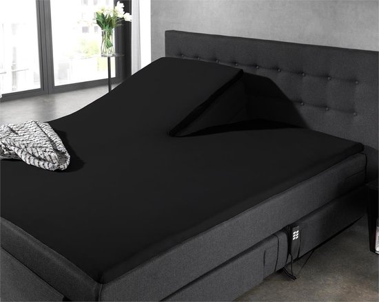 Een verstelbaar zwart bed met een gedraaid hoeslaken en een deken.