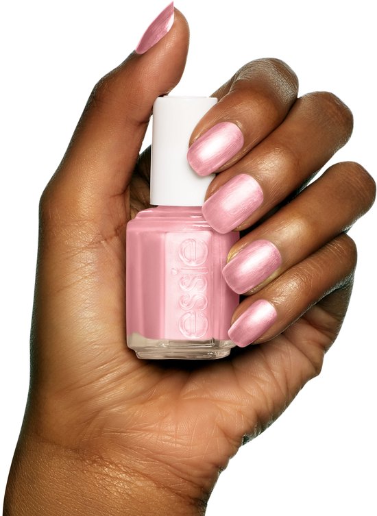 Een donkere huidskleurige hand met een parelmoer roze Essie nagellak op de nagels en een flesje in de palm.