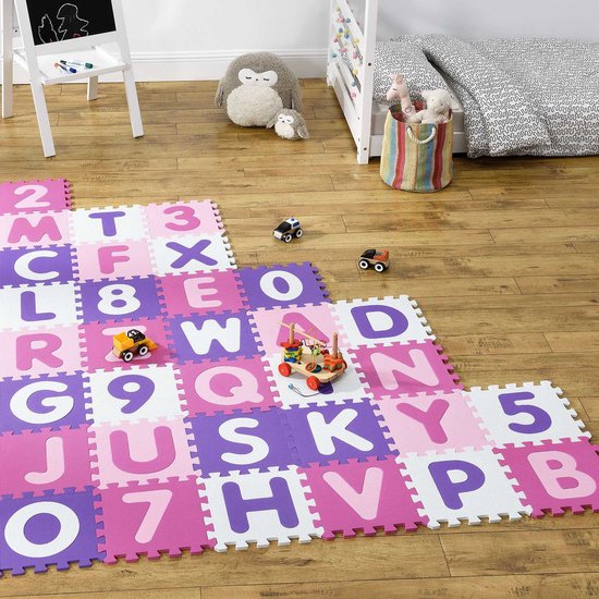 Roze en paarse puzzelmat met letters en cijfers op een houten vloer, met speelgoed.
