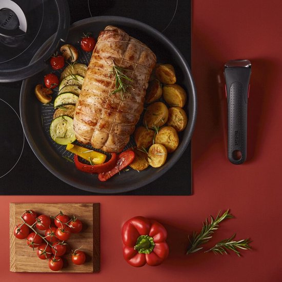 Geroosterd vlees met aardappelen, courgette, tomaten en champignons in een zwarte koekenpan met een afneembare handgreep.