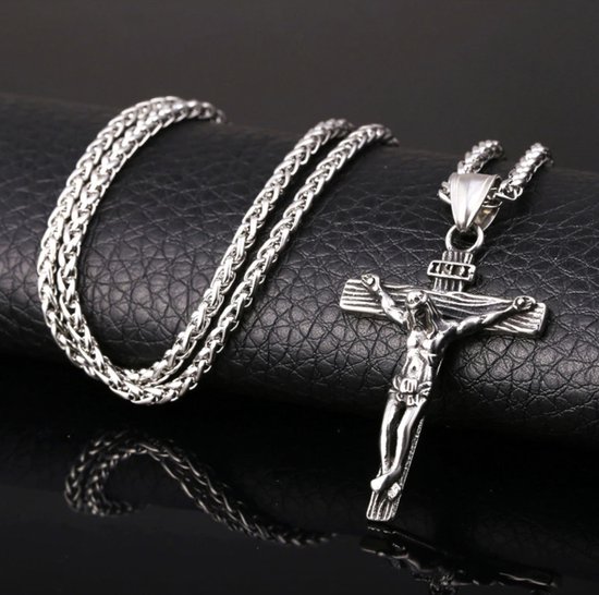 Zilverkleurige ketting met kruisje van Jezus, I.N.R.I. opschrift, op een zwarte achtergrond met textuur.