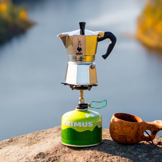 Bialetti Moka Express espressopot op een campinggasstel, buiten op een rots met uitzicht op water.