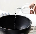 Zwarte tafelgrill met een hand die water in de kuip giet.