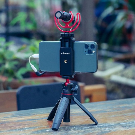 Set voor smartphone-opnamen met telefoon, microfoon en statief op een tafel.