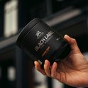 Hand houdt pot met oranje XXL Nutrition Black Label Pre Workout (390 g) vast.