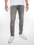 Man met grijze slim fit jeans, wit T-shirt en witte sneakers. De jeans heeft omgeslagen broekspijpen.