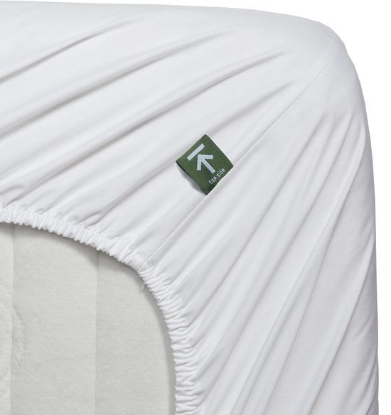 Drap-housse blanc pour topper avec une étiquette verte indiquant 'top side'.