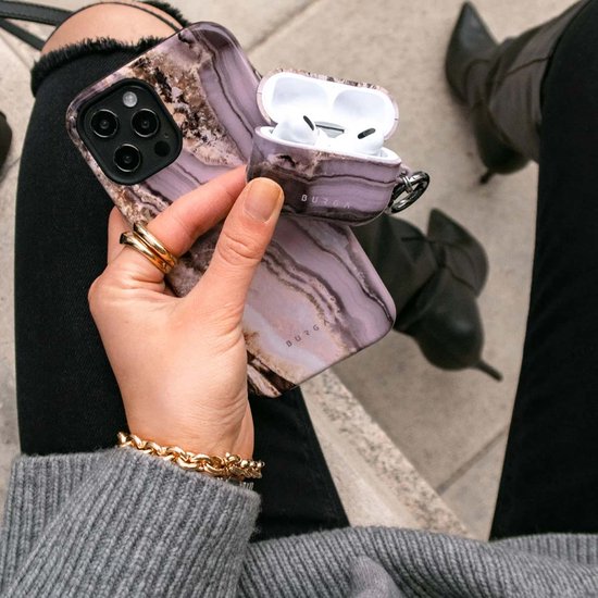Hand die een telefoonhoesje met agaatpatroon en een bijpassend hoesje voor AirPods vasthoudt.