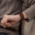Zwart en oranje siliconen horlogebandje met ronde perforaties om de pols.