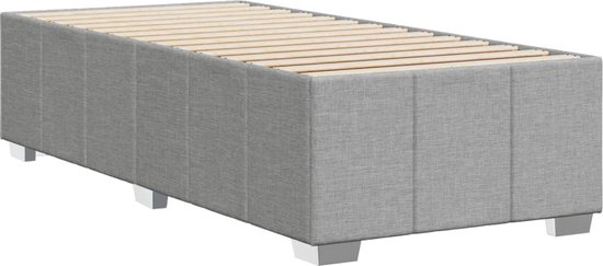 Cadre de lit gris clair en tissu avec sommier à lattes et pieds carrés en métal, vu de trois quarts avant.