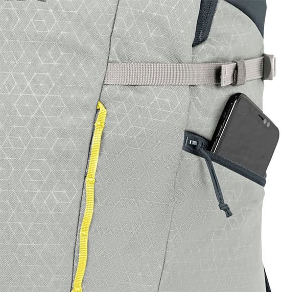 Grijze rugzak met geometrisch patroon, een geel lusje en een zijvak met rits waarin een smartphone zit.
