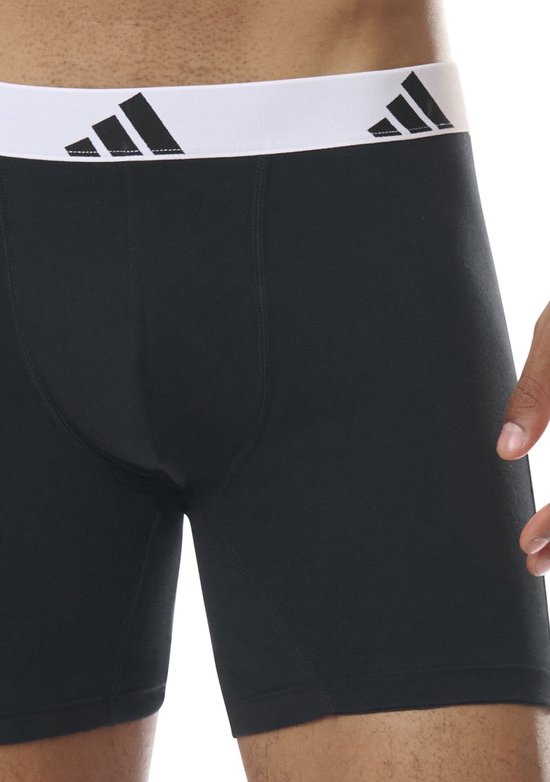 Detail van zwarte boxershorts met brede, witte Adidas-band met logo's.