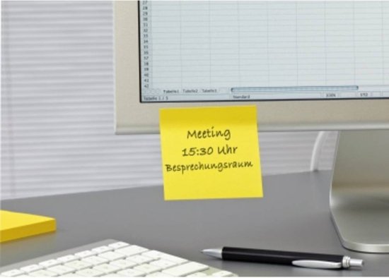 Een gele Post-it notitie met de tekst "Meeting 15:30 Uhr Besprechungsraum" op een computerscherm.