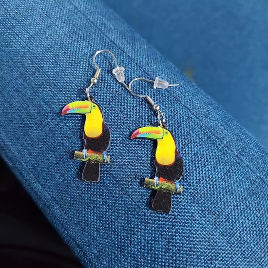 Boucles d'oreilles toucan, avec poitrine jaune, plumes noires et bec coloré, assis sur une branche.