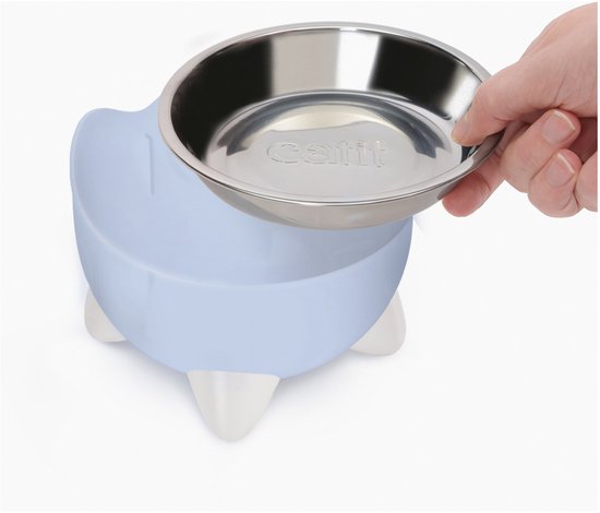 Hand vult een blauwe Catit Pixi voerbak met metalen binnenkant, op witte pootjes.