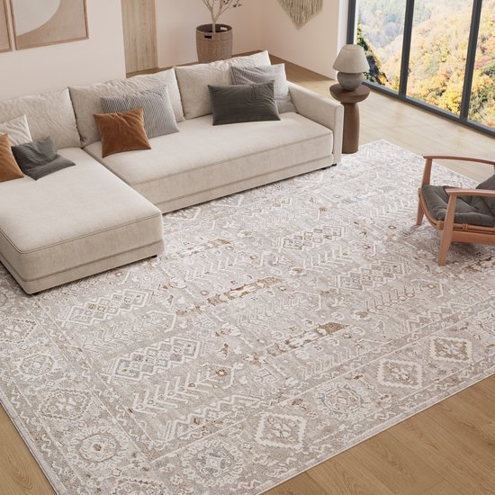 Un tapis crème avec motif géométrique vintage en beige et brun clair, placé dans un salon.