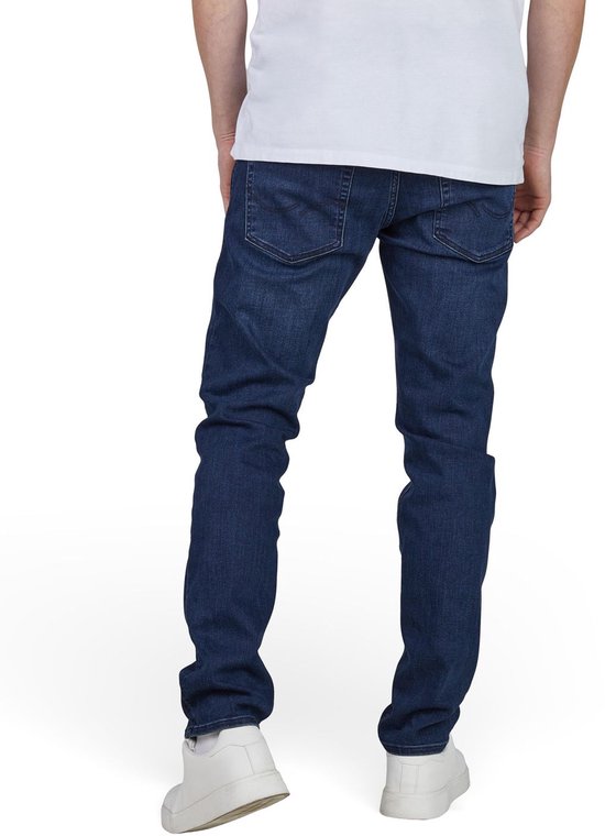 Man van achteren, gekleed in een donkerblauwe slim fit spijkerbroek en witte sneakers.