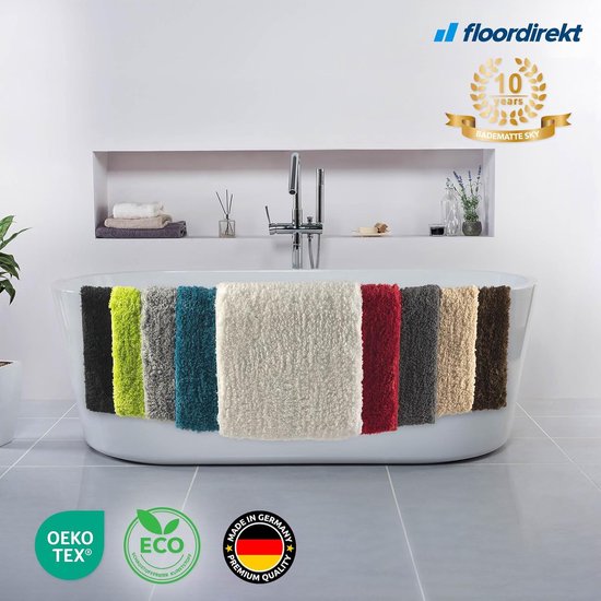 Vue d'ensemble de neuf tapis de bain de différentes couleurs, dont cette variante crème 'Sky', sur le bord d'une baignoire.