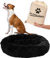Een bruin-witte hond zit naast een zwart, pluizig donut hondenbed, met een zak met de tekst "All 4 Pets Supply" ernaast.