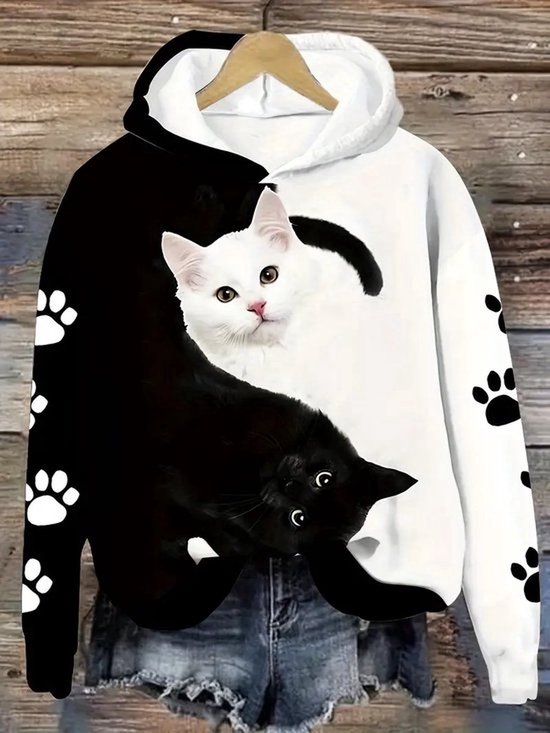 Zwarte en witte hoodie met twee kattenprint op de voorkant en pootafdrukken op de mouwen.