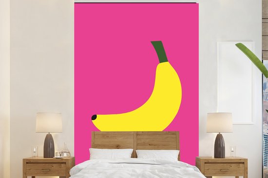 Een grote gele banaan met groene steel op een fuchsia achtergrond boven een bed met houten hoofdeinde.