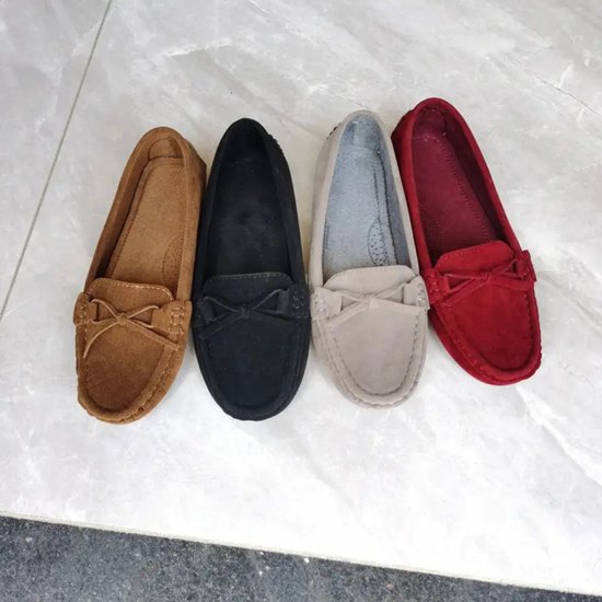 Vier suède loafers in bruin, zwart, grijs en rood, elk met een strikje op de wreef.
